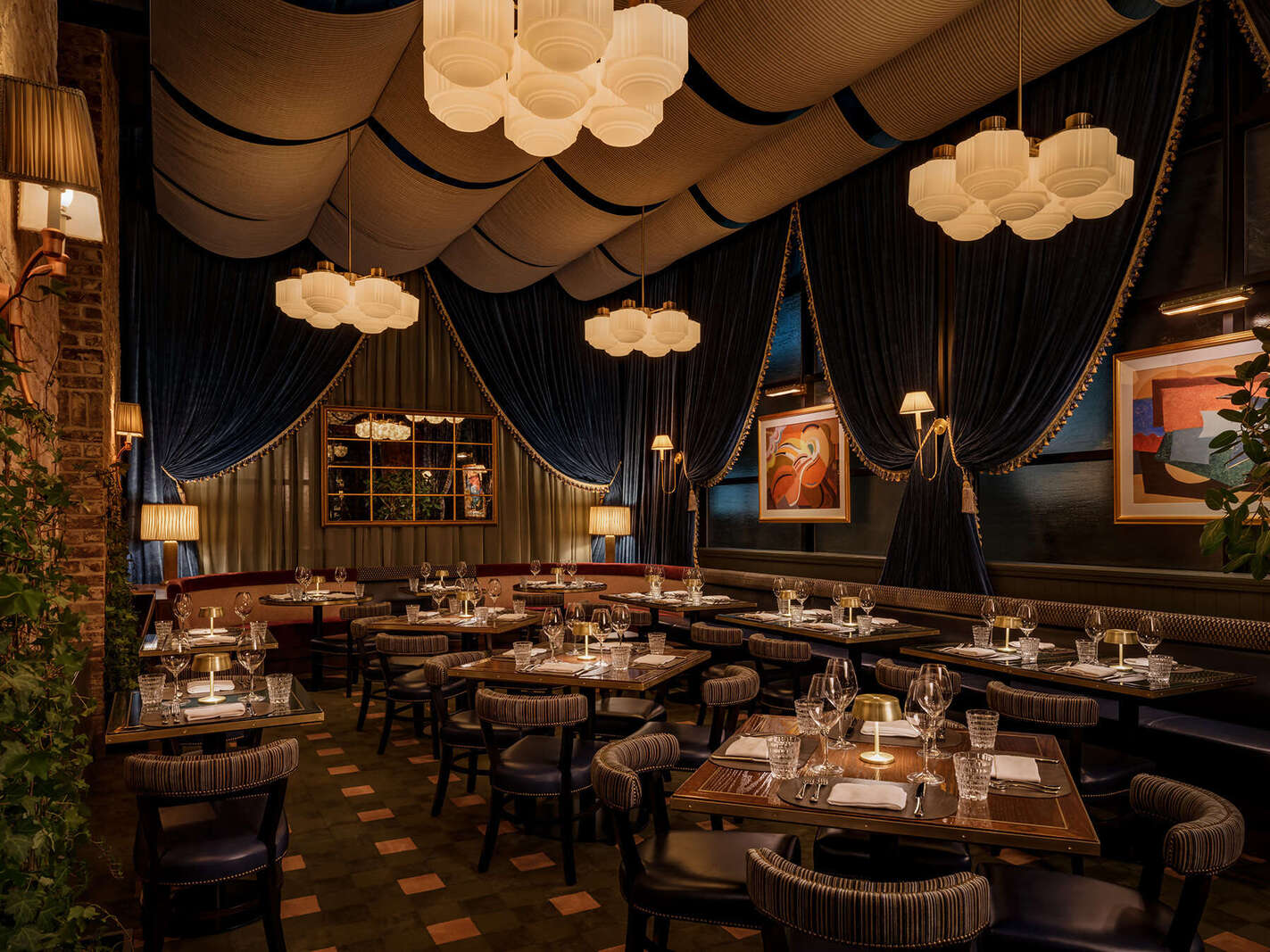 Elegant steakhouse dining room with chandeliers, marble tile floor, and warmly lit tables.